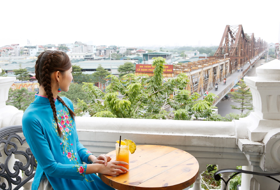 セランカフェ＆ラウンジのテラス席からロンビエン橋を眺める女性